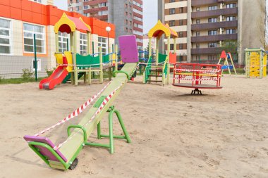 Karantina ve salgın covid-19 döneminde kapalı bir oyun parkında çocuk ve bant bariyeri için sallanmak