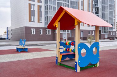 Oyun parkında yeni bir apartmanın arka planına karşı küçük bir oyun evi.