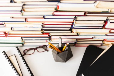Ders kitabı, dizüstü bilgisayar, gözlük, yığın yığın edebiyat, kitaplık