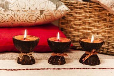 Hindistan cevizi kabuğunda, yastıkta ve ekosede yanan spa aromalı mumlar.