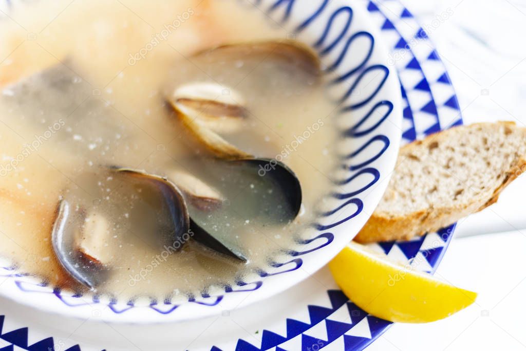 Seafood soup with mussels, prawns, fish in the white plate with 