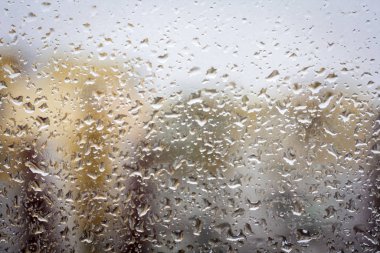 Camdaki yağmur damlaları, dışardaki binaların pencere arkaplan görüntüsü