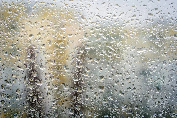 Raindrops on glass, window background view of buildings out of f — Stock Photo, Image