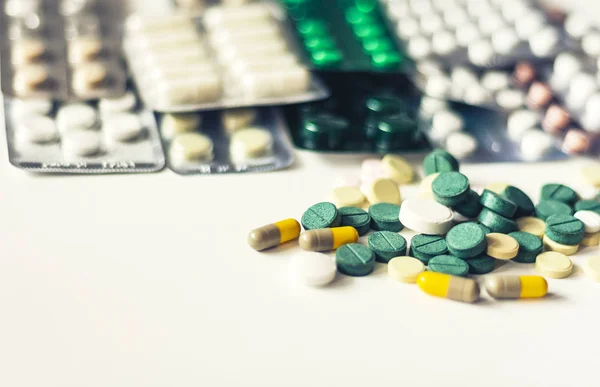 Gyógyszer zöld, rózsaszín és sárga tabletták vagy kapszulák fehér háton — Stock Fotó