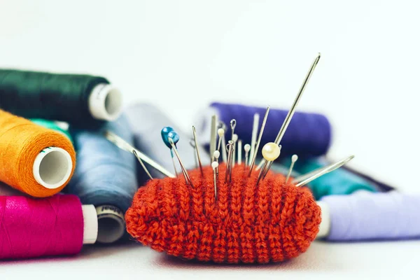 Tapis à aiguille tricoté rouge pour la couture et les bobines de fil coloré sur wh — Photo