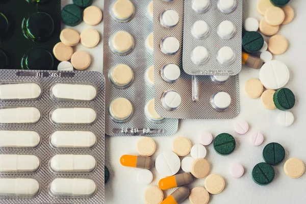 Medicamentos píldoras o cápsulas verdes, rosadas y amarillas sobre respaldo blanco — Foto de Stock