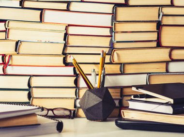 Kitap yığını, defter, dizüstü bilgisayar, ofis arka planında gözlük...