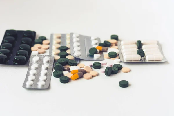 Medicamentos píldoras o cápsulas verdes, rosadas y amarillas sobre respaldo blanco — Foto de Stock