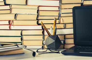 Kitap yığını, defter, dizüstü bilgisayar, ofis arka planında gözlük...
