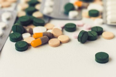 İlaç yeşili, pembe ve sarı haplar veya beyaz sırt kapsülleri