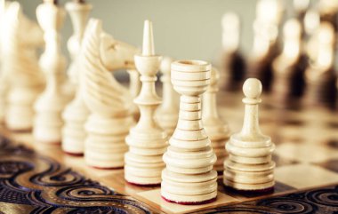 Satranç tahtasında tahta satranç taşları, beyaz üzerinde liderlik kavramı.