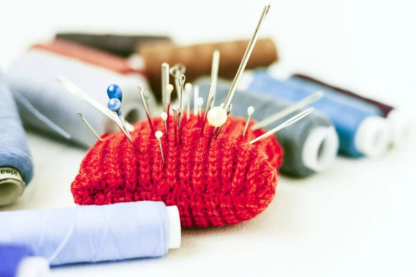 Tappetino rosso a maglia per cucire e bobine di filo colorate su wh — Foto Stock