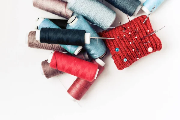Piros kötött tűvédő alátét varráshoz és színes cérna tekercsekhez — Stock Fotó