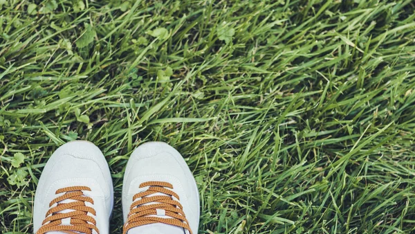 Par i sport skor i grå mocka på gräset i parken. — Stockfoto