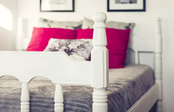 Letto in legno bianco intagliato con copriletto grigio e cuscini rossi  . — Foto Stock
