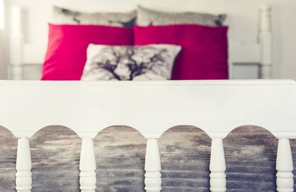 Letto in legno bianco intagliato con copriletto grigio e cuscini rossi  . — Foto Stock