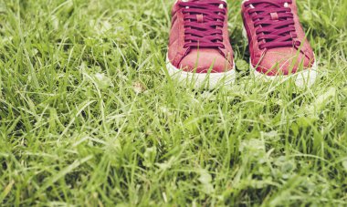 Parktaki çimlerin üzerinde pembe süet spor ayakkabılar..