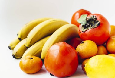 Beyaz arka planda meyve tabağı. Mandalina, muz, hurma 