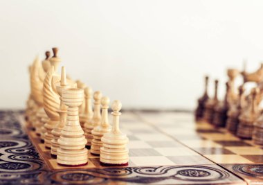 Satranç tahtasında tahta satranç taşları, beyaz üzerinde liderlik kavramı.