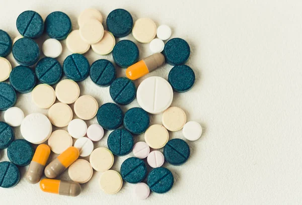 Gyógyszer zöld, rózsaszín és sárga tabletták vagy kapszulák fehér háton — Stock Fotó