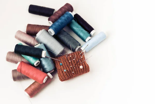 Tappetino rosso a maglia per cucire e bobine di filo colorate su wh — Foto Stock