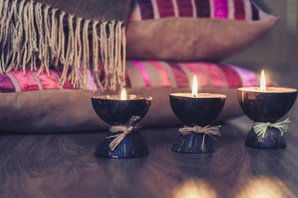 Velas ardientes de aroma spa en cáscara de coco y almohadas de color burdeos — Foto de Stock