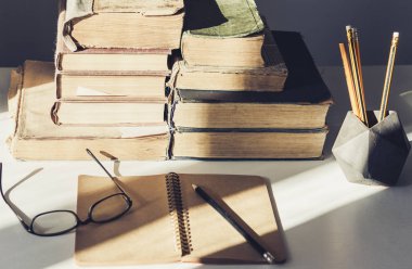 Ofiste bir yığın eski kitap, ders kitabı, bardak ve kalem var.