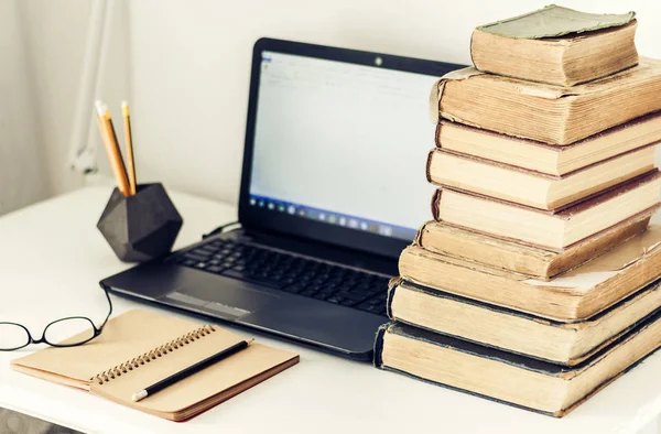 Laptop, pilha de livros antigos, caderno e lápis na mesa branca , — Fotografia de Stock