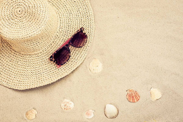 Straw hat and sun glasses on a tropical beach .