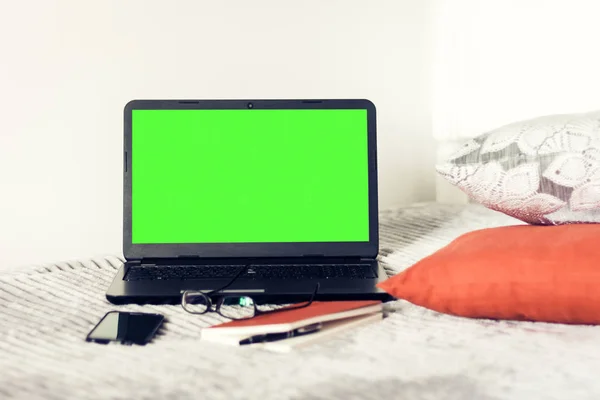 Green screen laptop, notebook, smartphone, glasses and pen on ba
