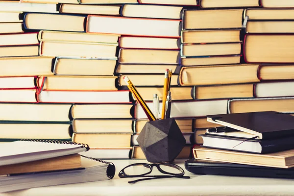 Stack of books, notebook, laptop, glasses in office background f