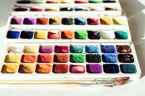 Akvarel barvy a štětce dobře používané na bílém dřevěném stole vtip — Stock fotografie