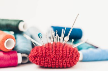 Dikiş için kırmızı örülmüş iğne yastığı ve renkli iplik bobinleri