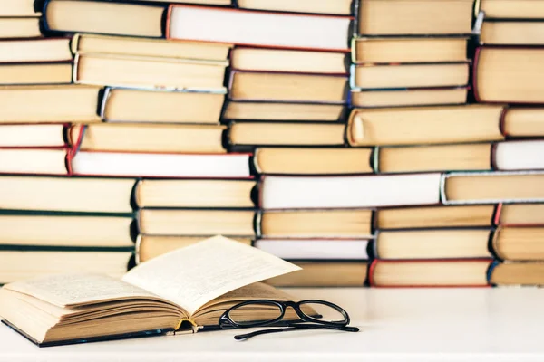 Libros de fondo, libro abierto y vasos sobre mesa de madera blanca en — Foto de Stock