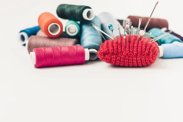 Tapis à aiguille tricoté rouge pour la couture et les bobines de fil coloré sur wh — Photo