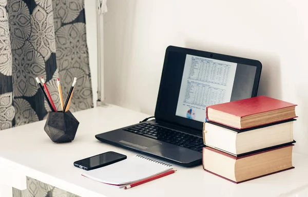 Laptop, Bücherstapel, Notizbuch, Smartphone im Büro — Stockfoto