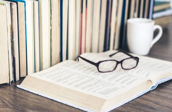 Pila de libros de educación de fondo, libro abierto, gafas y taza — Foto de Stock