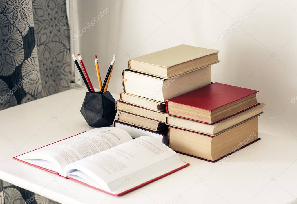 Stack of old books, textbook and pencils in office background fo