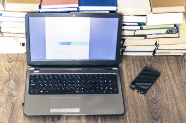 Kitap yığını, akıllı telefon, dizüstü bilgisayar, ofis işinde gözlük.