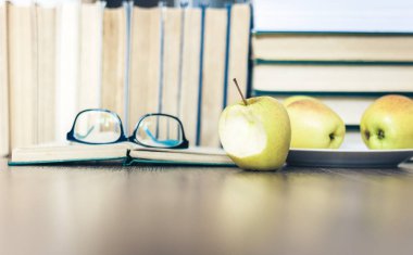 Kitap yığını, açık kitap, bardak ve yeşil elma, arkaplan 