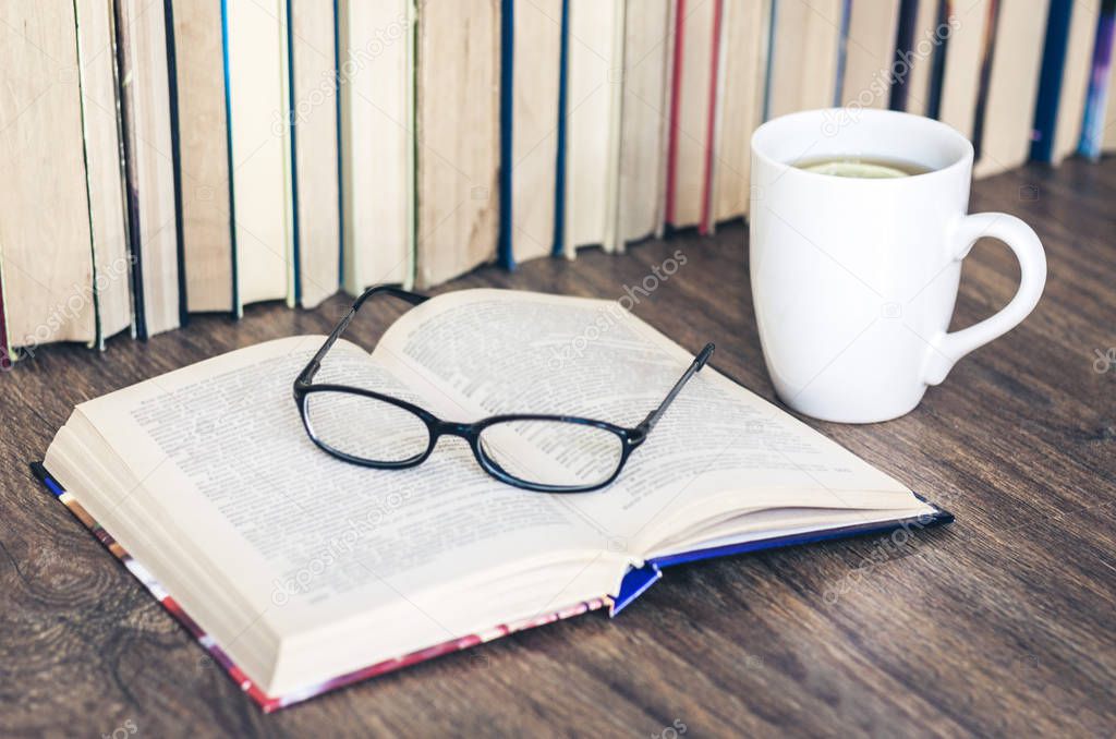 Stack of books education background, open book, glasses, and cup