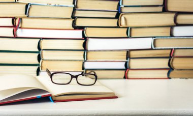 Kitap arkaplanı, açık kitap ve gözlük beyaz ahşap masa
