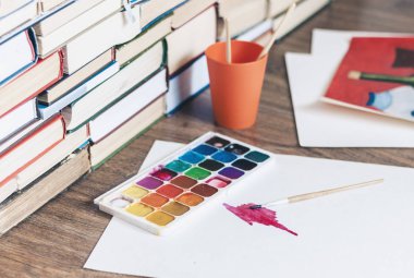 Suluboya boya, iyi kullanılmış fırçalar ve tahta üzerinde kağıt.