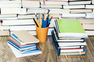 Tahtadaki plastik tutacakta kitap, defter ve kalemler yığını.