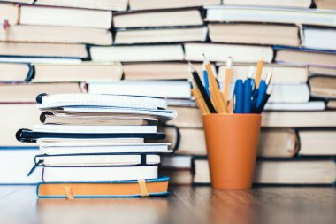 Tahtadaki plastik tutacakta kitap, defter ve kalemler yığını.
