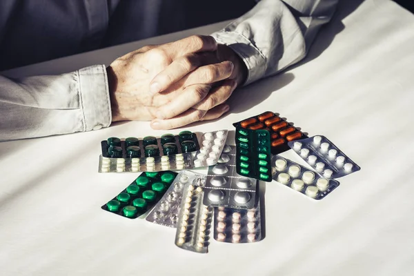 Léky pilulky nebo kapsle s rukou staré ženy na bílém bac — Stock fotografie
