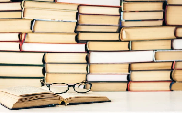 Könyvek háttér, nyitott könyv és szemüveg fehér fa asztal — Stock Fotó