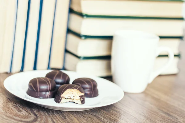 Stack of books, cup of coffee and chocolate cookies white plate. Stock Picture