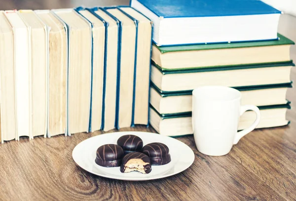 Stack of books, cup of coffee and chocolate cookies white plate. Royalty Free Stock Photos