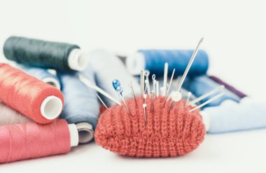 Dikiş için kırmızı örülmüş iğne yastığı ve renkli iplik bobinleri